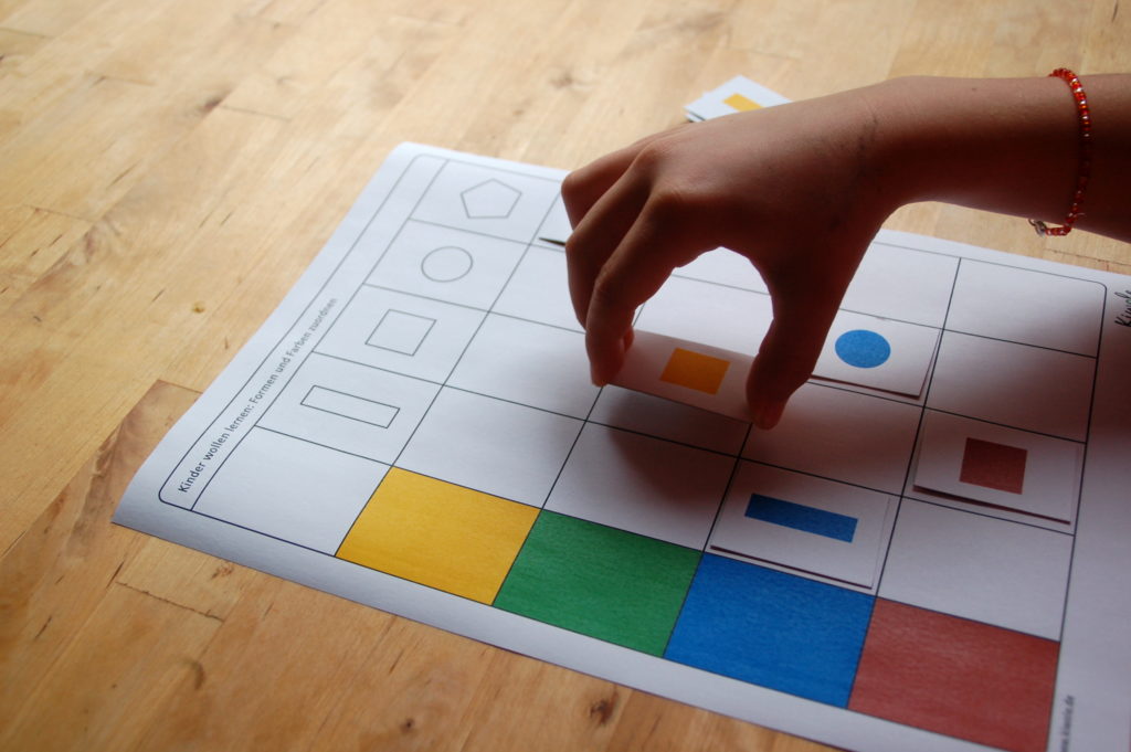 Foto von einem Kind, welches ein Lernspiel mit Farben und Formen spielt