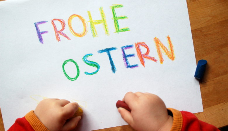 Foto von Kinderhänden, die "Frohe Ostern" aufgeschrieben haben