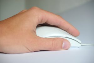 Foto von einer Hand mit einer Computermaus als Symbolbild für die Medienkompetenz