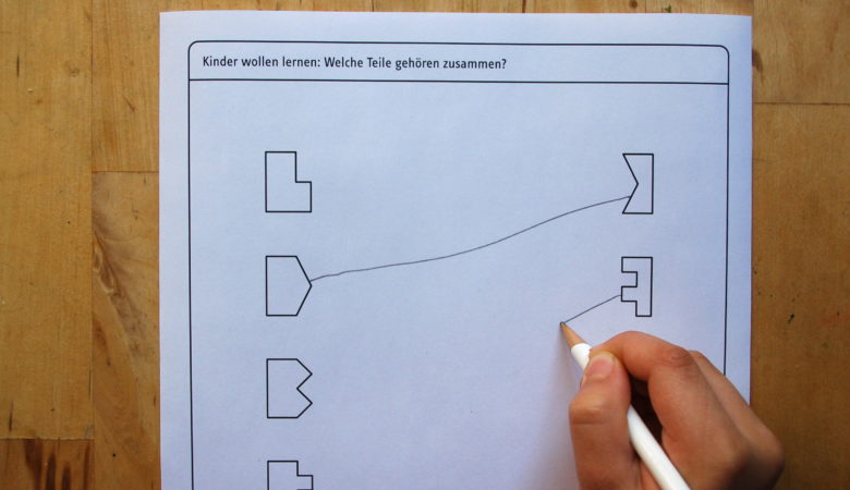 Foto von einem Kind, welches das Arbeitsblatt mit dem Kinderrätsel "welche Teile gehören zusammen?" löst