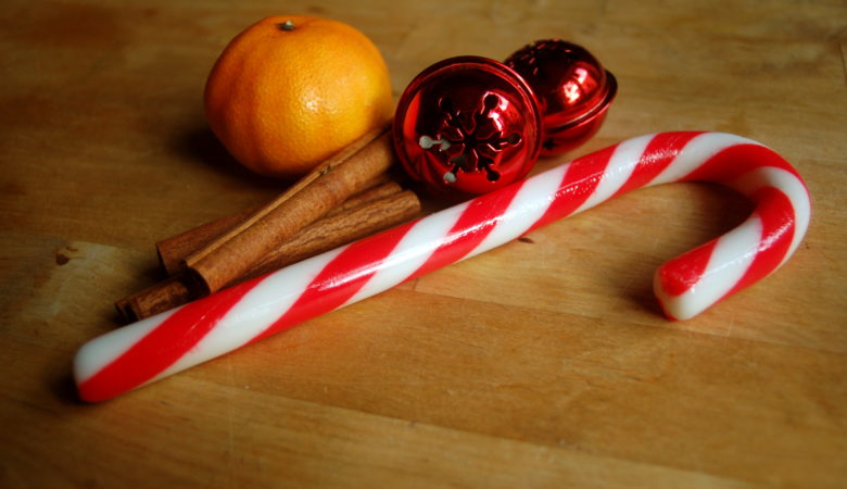 Foto von einer Zuckerstange, einer Zimtstange und einer Clementine passend zu Weihnachten