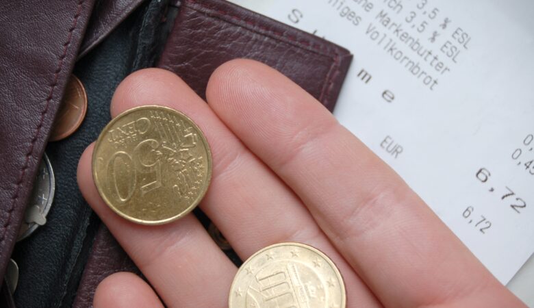 Einkaufen will gelernt sein: Das Foto zeigt einen Kassenbon sowie eine Hand mit Kleingeld