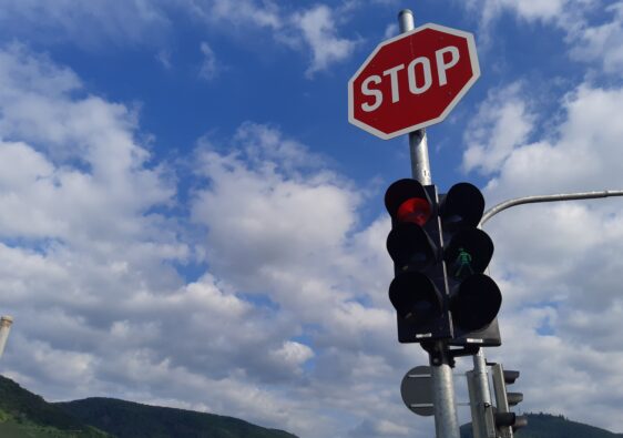 Eine Ampel mit Stoppschild vor blauem Himmel als Symbolbild für die Verkehrserziehung