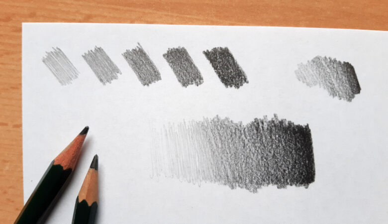 Foto von zwei Bleistiften auf einem Blatt Papier, auf dem Versuche zum Thema Grauwerte / Tonwerte zu sehen sind